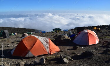 Camping in an orange tent on the Lemosho route while trekking Mount Kilimanjaro in Tanzania