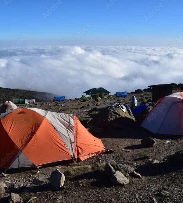 Camping in an orange tent on the Lemosho route while trekking Mount Kilimanjaro in Tanzania