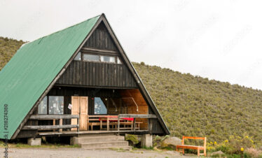 Mountain cabin with deck on a hillside with clouds