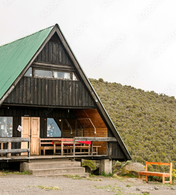 Mountain cabin with deck on a hillside with clouds