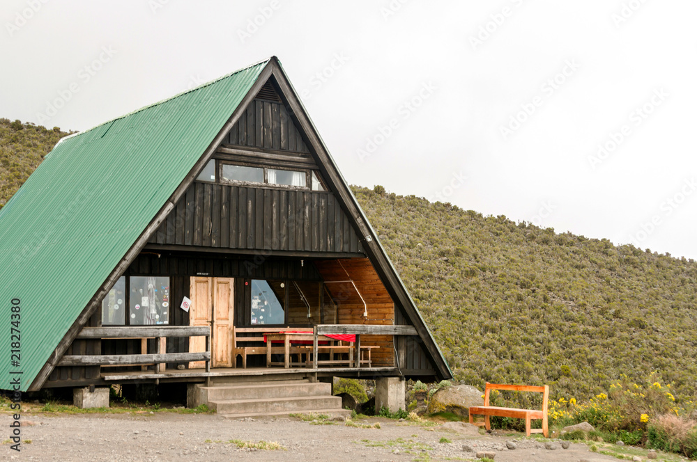 Mountain cabin with deck on a hillside with clouds