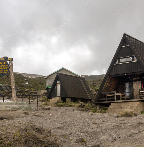 Mountain cabins and trail marker sign on a plateau campsite