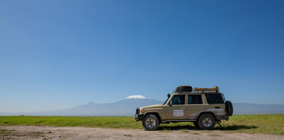 Toyota Land Cruiser on open terrain with Mount Kilimanjaro in the distance.