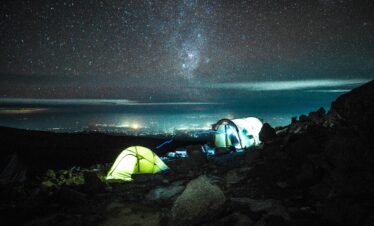 Illuminated tents on Kilimanjaro under a stunning starry sky, capturing the essence of nighttime adventure.