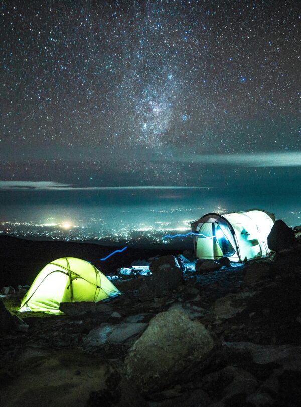 Illuminated tents on Kilimanjaro under a stunning starry sky, capturing the essence of nighttime adventure.