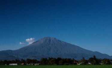 Scenic view of Mount Meru against a clear blue sky in Tanzania, showcasing its volcanic landscape.